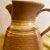 Artist signed clay pitcher with stripes and speckling in shades of cream and browns. Very nice shape to it.