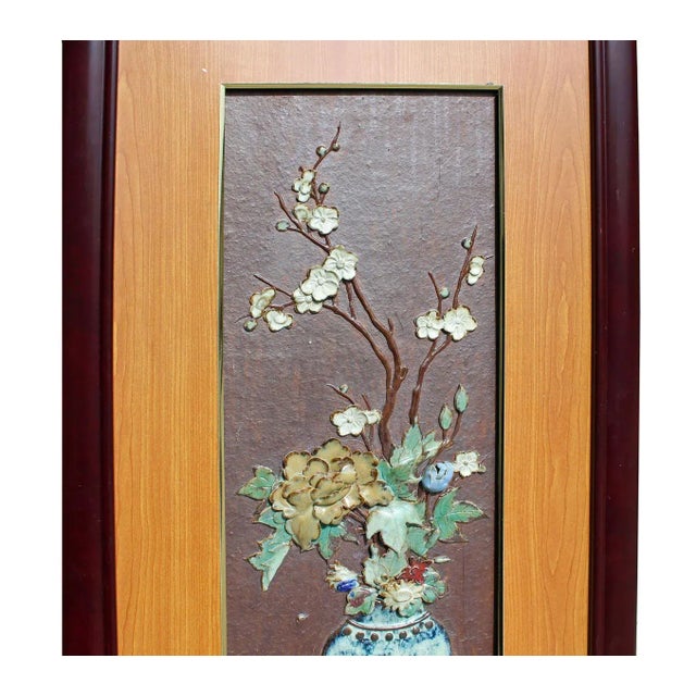 This is a ceramic piece with dimensional theme of oriental flowers and vases. This plaque is installed with wooden frame...