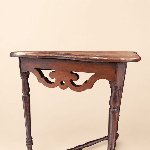 A half-moon console with the kind of quiet formality that anchors an entryway. The apron is a pierced fretwork band of...