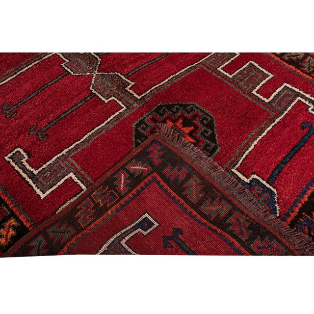 Beautiful vintage Turkish hand-knotted wool rug with a red field. This Turkish rug has a brown frame and navy-blue,...