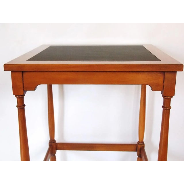 Modernist walnut table featuring a simple apron and straight round legs with arrow feet. Pecan finish with black top....