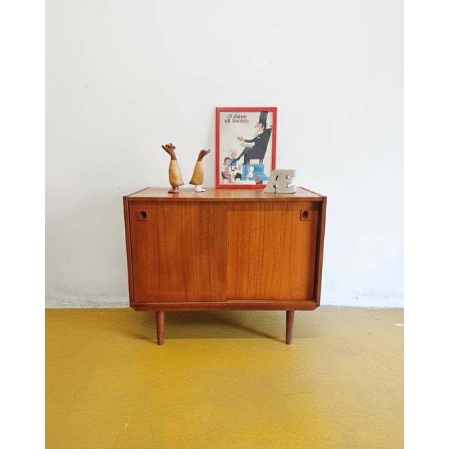 A vintage Danish teak sideboard from the 1950s with sliding doors and an elegant, compact design, perfect for a functional...
