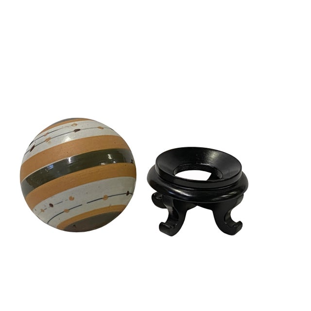 This is a simple tan beige olive mixed color stripe pattern porcelain ball display . Dimensions: Ball Dia 4" with stand...