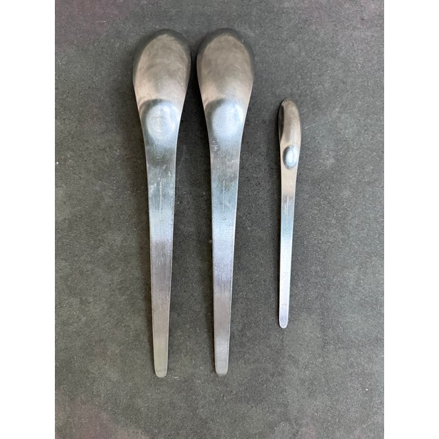 Set of three spoons, two Serving at 11” and one teaspoon at 7 1/4”. All three utensils are marked with the manufacturer’s...
