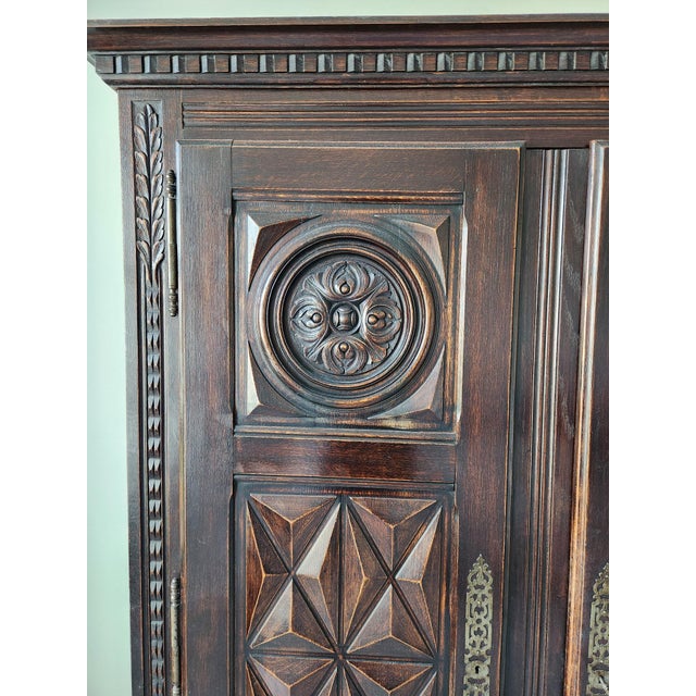 Striking antique three-door cabinet featuring exceptional hand-carved craftsmanship throughout. The façade showcases bold...