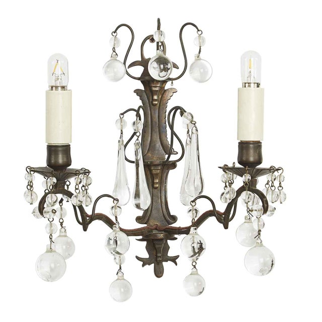 A pair of early 1900s brass and crystal wall lamps, consisting of a shaped cast plate supporting three small brackets,...