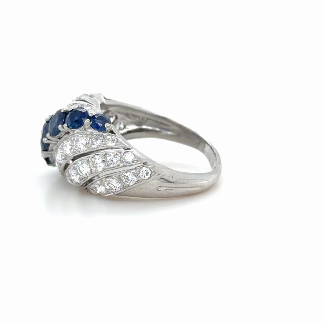 This beautifully classic ring by Tiffany & Co. in an elegant swirl design, boasts seven bright blue round brilliant cut...