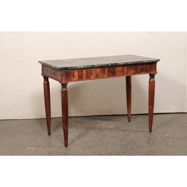 An elegant Italian wooden console table, with marble top, from the early 19th century. This antique table from Italy...