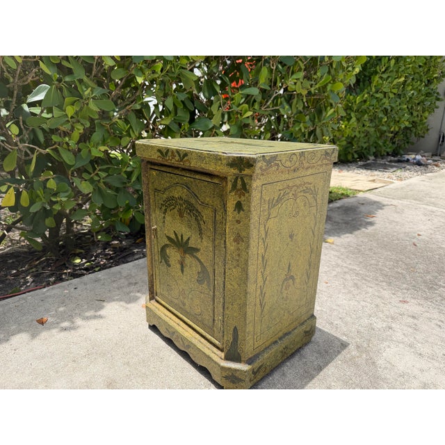 Vintage hand-painted Florentine style commode cabinet featuring an antiqued green finish with decorative floral and...