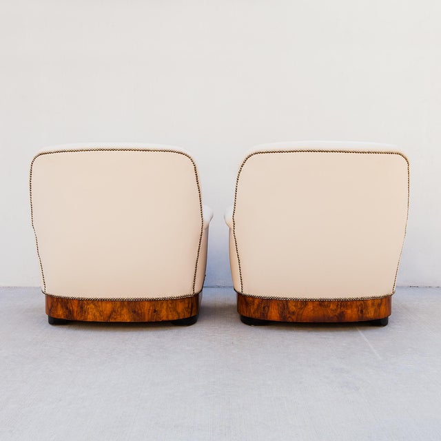 A newly restored pair of Continental Art Deco high-back lounge chairs in burl walnut and Edelman leather with nailhead...