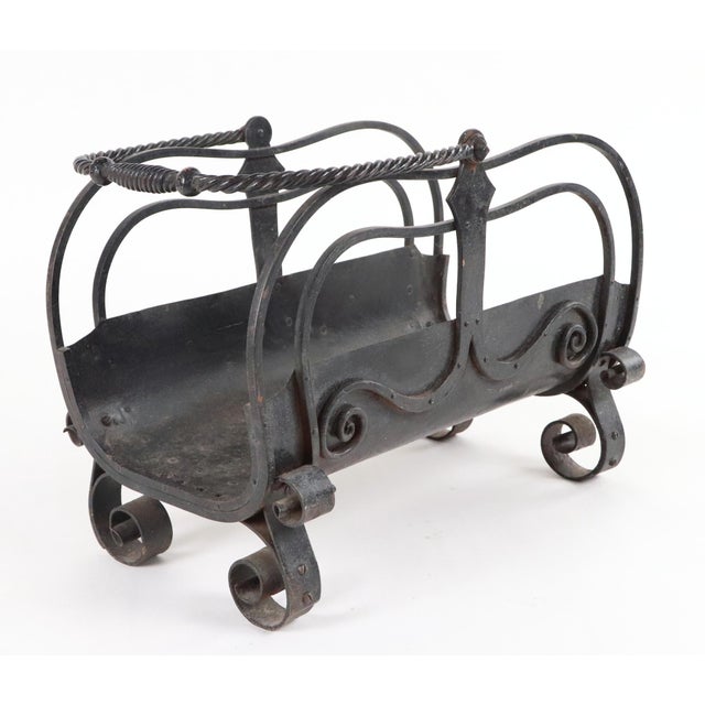 Arts & Crafts hand wrought iron log basket with a twisted handle and forged scrollwork on the sides and feet. There is...