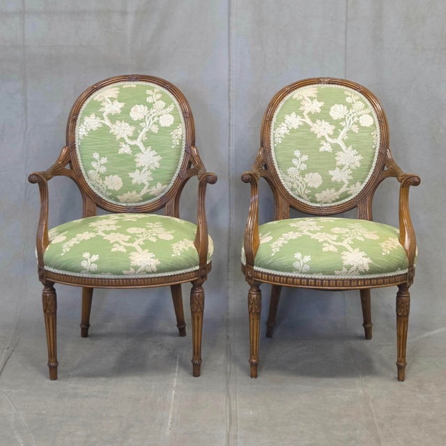 A stunning pair of vintage 1990s French Louis XVI style carved wood armchairs (fauteuils) featuring round medallion backs,...