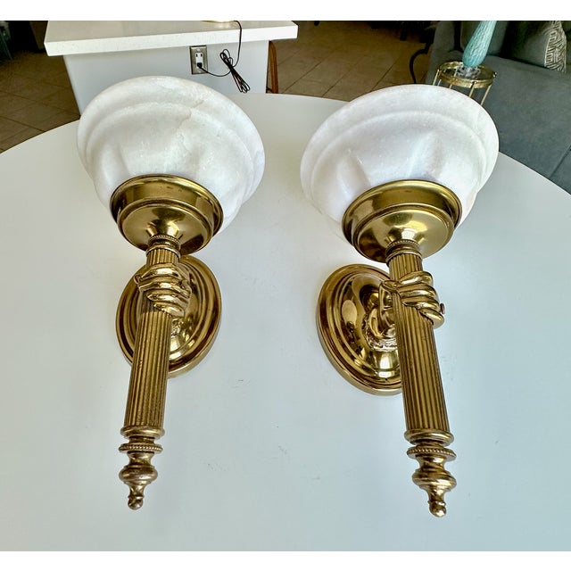 Pair French 1950's brass wall sconces of hands holding a torch with alabaster shade, attributed to John Devoluy. The hand...