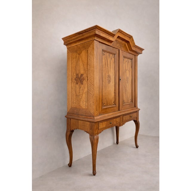 An elegant late 18th century Baroque cabinet crafted in walnut with beautifully executed floral marquetry panels. Likely...