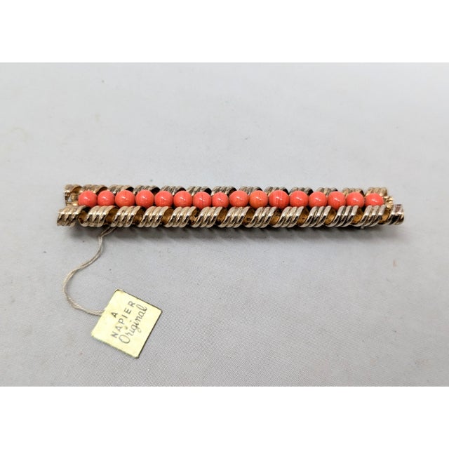 1960s goldtone curled edges with a line of faux-coral beads down the center bar brooch with security clasp. Marked...