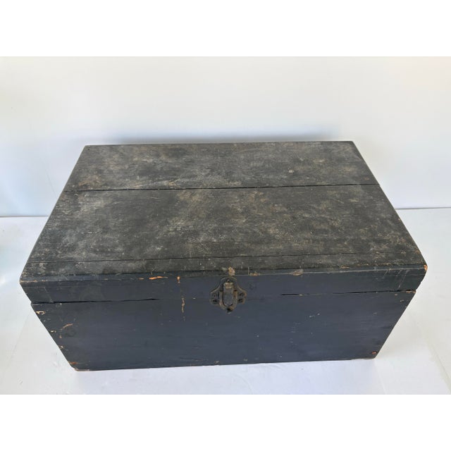 This early 20th-century primitive wooden storage chest features its original black painted finish, wonderfully timeworn...