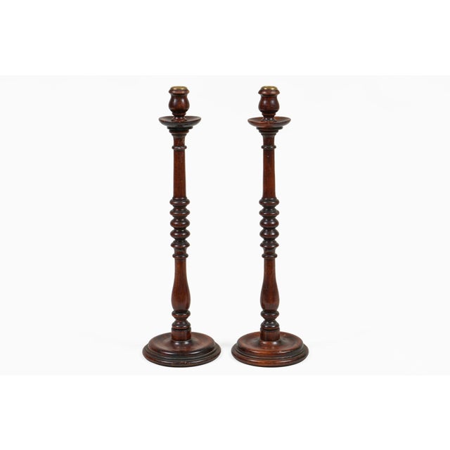 Antique pair of tall mahogany candlesticks, the column having a baluster turning at the base that rises to five ring...