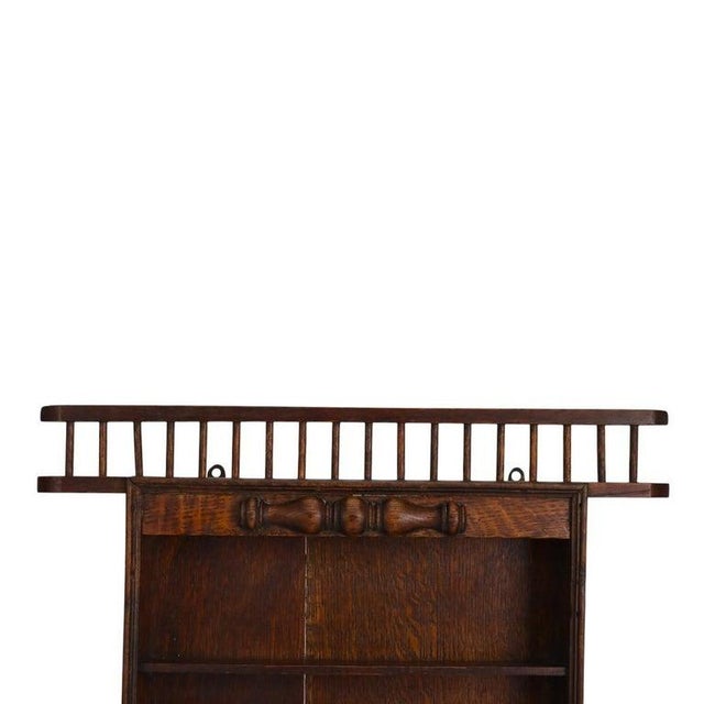 An antique oak display rack, likely dating to circa 1910, crafted from quarter-sawn oak with a rich, dark finish. This...