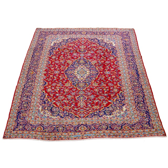 This Persian Kashan handmade wool rug has a red field with multicolor accents throughout the design. This rug measures...