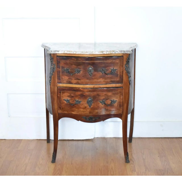 An antique, late 19th-century two-drawer dresser, commode, or chest of drawers in the French Louis XV style with a curved...