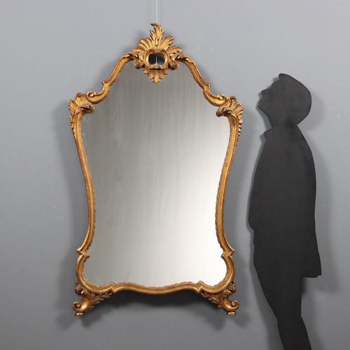 A carved and gilded late Baroque mirror. The frame is carved with scrolls, curls, and leaves. Italy, late 19th century....