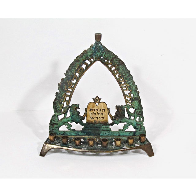 A richly detailed vintage brass Hanukkah menorah, made in Israel and marked R.D. 649 on the reverse. The piece features an...