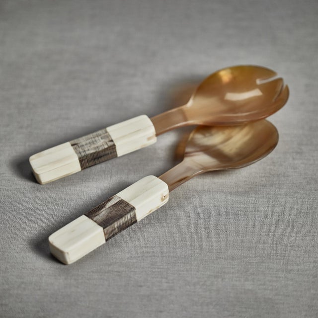 Beautifully crafted horn salad servers, each utensil features a simple shape with a finish that accentuates the horn's...