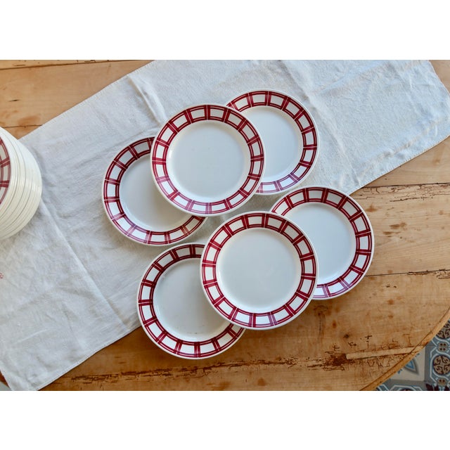 A beautiful set of six ironstone dinner plates from the Badonviller pottery, decorated with an elegant red geometric...