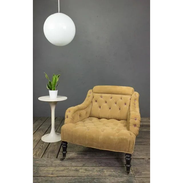 A handsome French armchair dating to the 19th century, featuring deep tufted suede upholstery accented with distinctive...