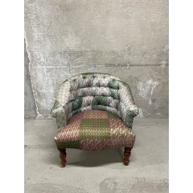 This traditional tufted tub chair features a mixed green and pink patchwork ikat style geometric patterned fabric. The...