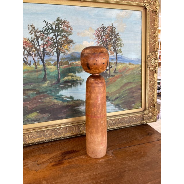 This vintage Japanese Kokeshi doll features a minimalist cylindrical form with a rounded head and hand-painted facial...