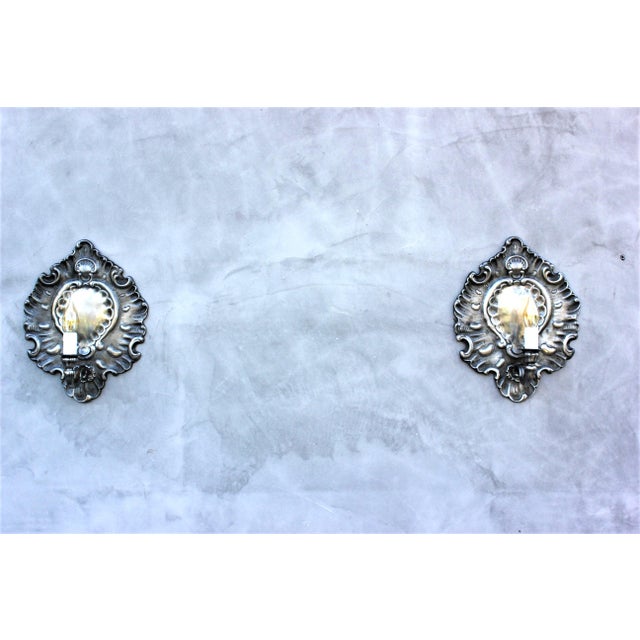 An elegant pair of Italian Rococo Revival wall sconces dating from the mid-20th century, crafted from cast zinc with a...