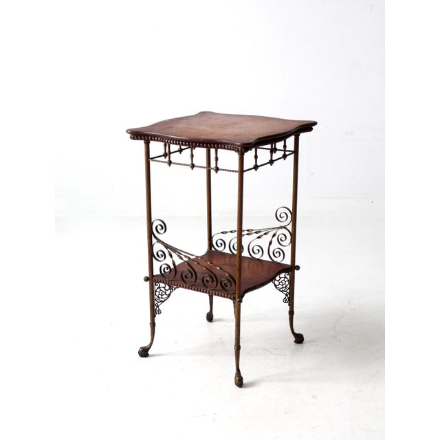 This is an antique wood and brass side table. The Victorian era stand features a decorative brass frame, paw feet, with a...