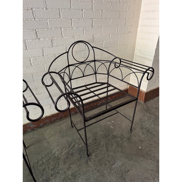 Unique pair of hand forged wrought iron garden chairs with scroll work arms. Most likely from the 60's or 70's.