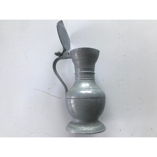 Tin jug with a lid, decorated with acorns. Signed with a coat of arms on the bottom. Height: - 17cm. Width - 11cm. ball...