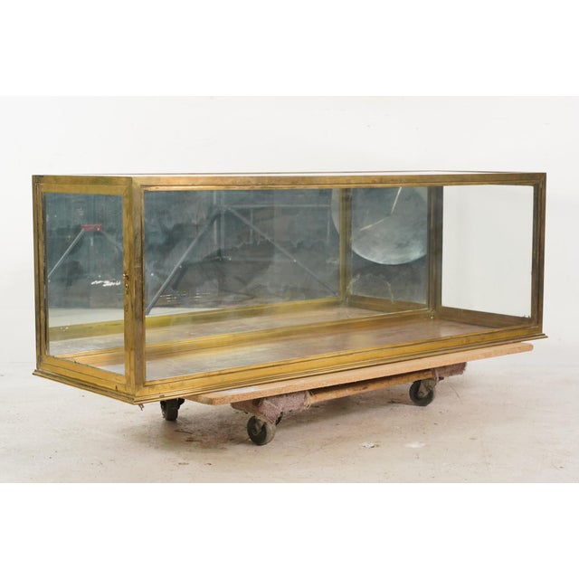 Vintage tabletop display case made of a brass frame, clear glass panels, and a mirrored back. The side panels open to...