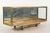 Vintage tabletop display case made of a brass frame, clear glass panels, and a mirrored back. The side panels open to...