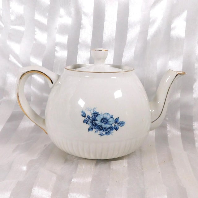 This is a Wood and Sons teapot in an unknown pattern. The teapot is white with a blue floral design on the front and a...