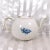 This is a Wood and Sons teapot in an unknown pattern. The teapot is white with a blue floral design on the front and a...