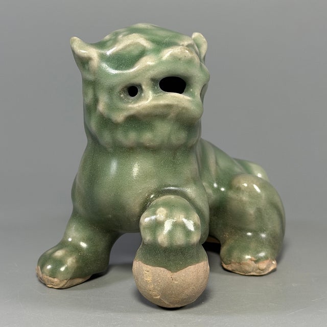 This is a handmade Chinese Longquan celadon ceramic lion ornament with delicate carved‑out details. Natural earth‑patina...