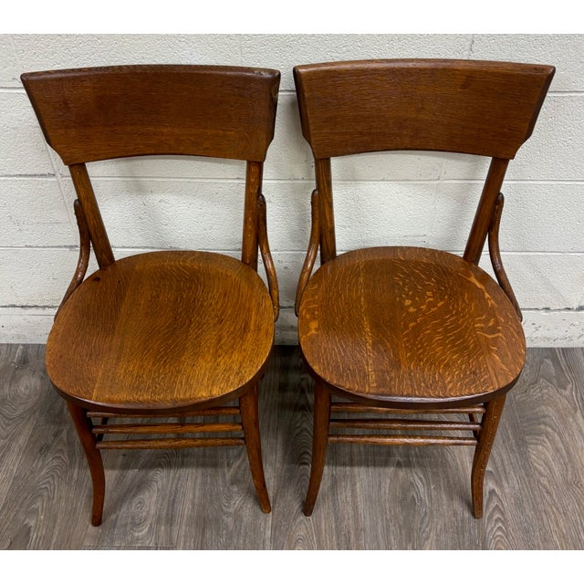This is a striking pair of antique bent oak dining chairs dating to the early 20th century. Each features a broad curved...