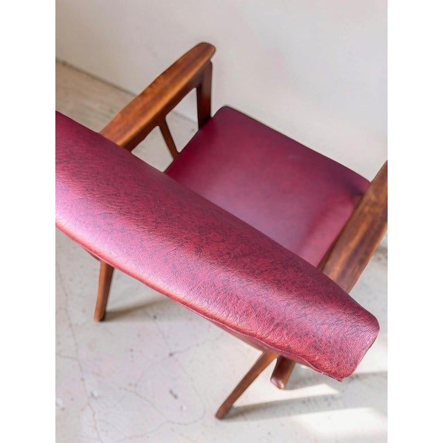 Set of 2 unique vintage armchairs from the 1960s. The chairs feature red faux-leather (skai) upholstery and a teak wood...