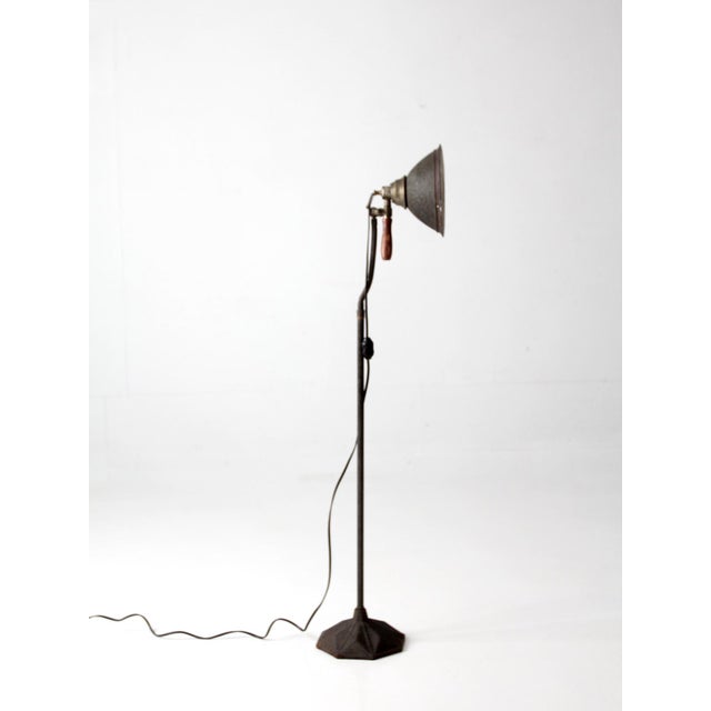 This early 20th century industrial task lamp features a cast iron base, adjustable gooseneck arm, spun metal shade, and...