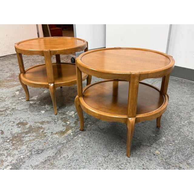Design Plus Gallery presents a Pair of Mid 20th Century Two-Tiered Side Tables. This matching pair showcases round tops...