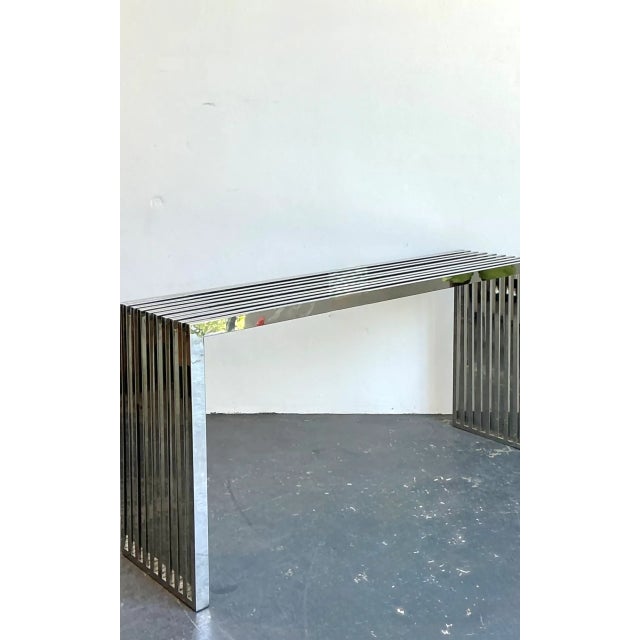 This vintage chrome slat console table brings a crisp, architectural presence to an interior, pairing a sleek modern...