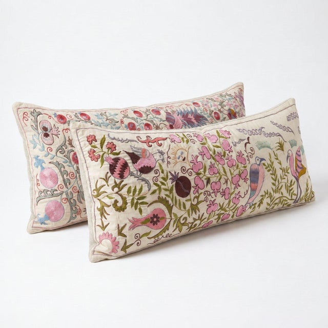 An extra-long lumbar pillow cover set made from hand-embroidered Uzbek Suzani cotton — hand-embroidered pink blossoms,...