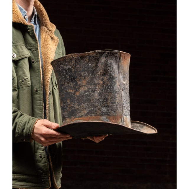 Large-scale tin top hat form with exaggerated proportions, featuring a tall cylindrical crown and wide, gently flared...