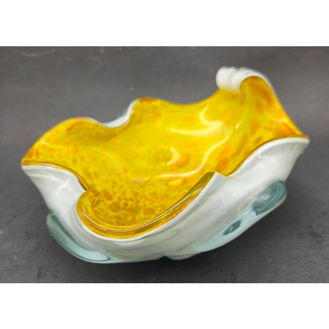 Offered is a mid 20th Century hand-blown cased art glass bowl featuring a vibrant yellow interior with aventurine or gold...