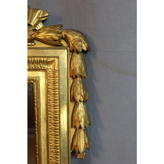 Large Louis XVI period giltwood mirror. The pediment is decorated with a large bow, the gilding is original, and the glass...