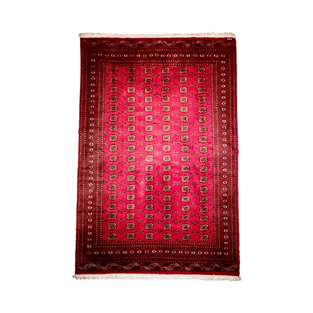 Authentic hand-knotted Persian rug featuring a classic repeating gul (Bokhara-style) pattern in rich crimson red with dark...